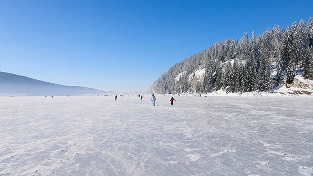 Schlittschuhfahrende Menschen auf dem Lac de Joux im verschneiten Winter