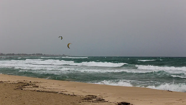 Kitesurfer reiten auf den Wellen unweit vom apulischen Tarent. Der Schirokko kann das Meer ordentlich aufwühlen.