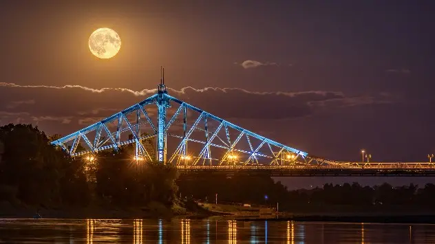 Supermoon rises over bridge and river in Dresden, Germany.