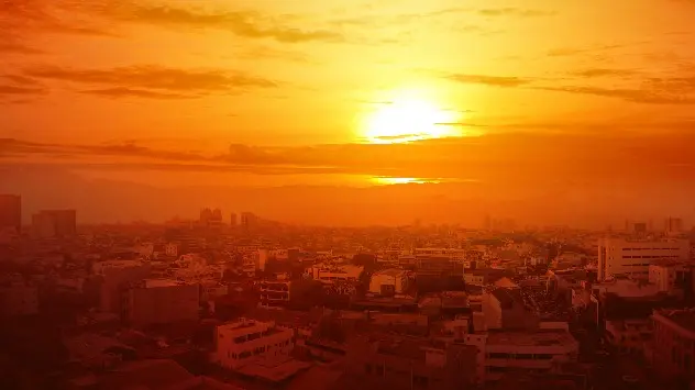 Die Sonne taucht eine Stadt in warmes, orange-rotes Licht.