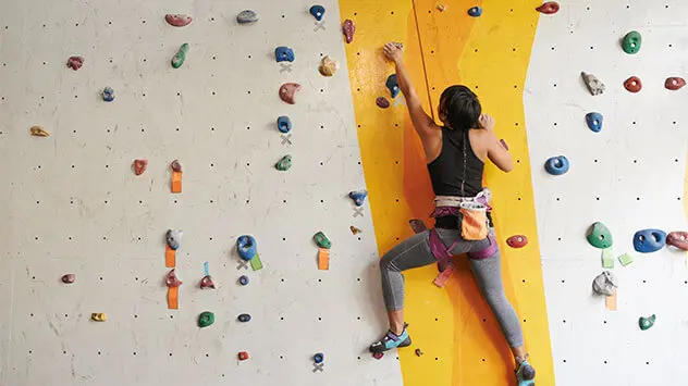 Frau klettert an einer Indoor-Kletterwand
