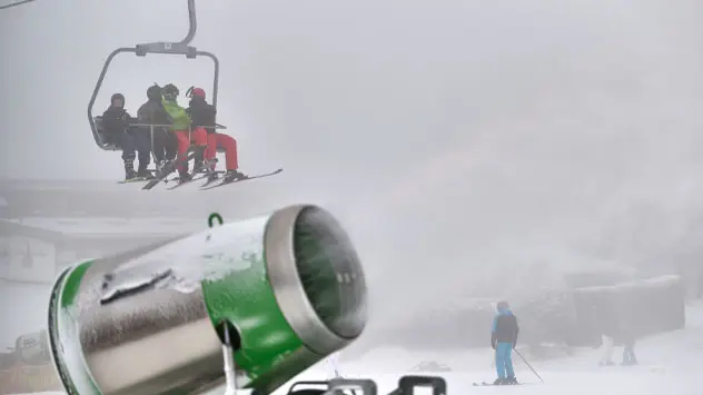 Wintersporters gaan op pad in de skilift over een kunstmatig besneeuwde helling op de Remmerswiese. 