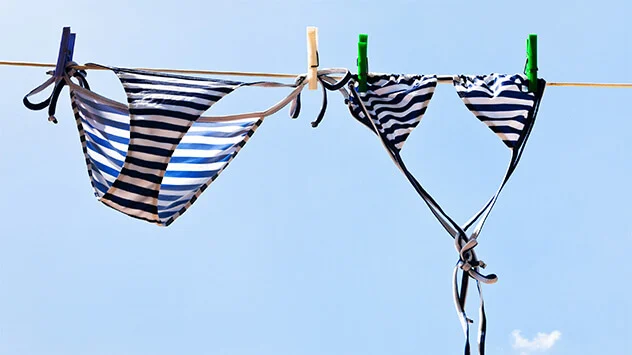 Blauer Bikini hängt auf einer Leine zum Trocknen