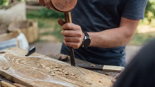 Meißel und Hammer bearbeiten ein Stück Holz