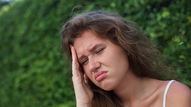Frau fasst sich mit schmerzverzerrtem Gesicht