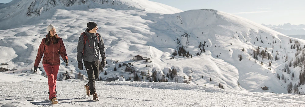 Ein Paar unternimmt eine Winterwanderung bei Sonnenschein. 