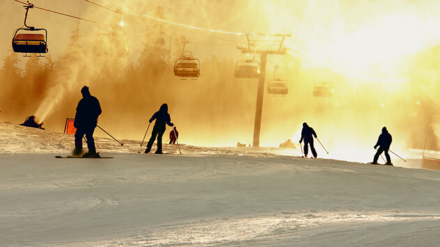Skifahrer auf Abfahrtspiste im goldenen Sonnenlicht