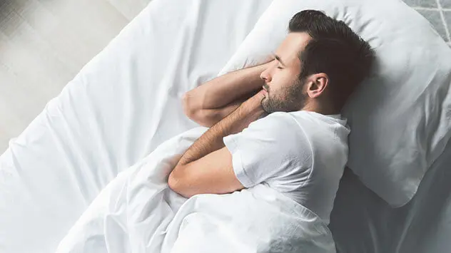 Mann schläft in T-Shirt in einem Bett