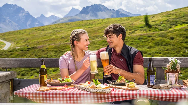 Ein Paar genieß eine Brotzeit auf einer Almhütte