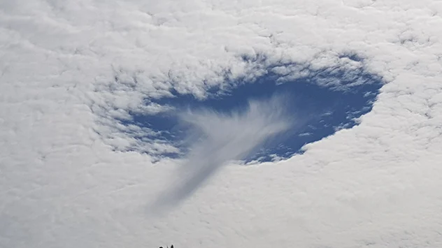 Mitten im Wolkenloch zeigt sich eine herabhängende, zerfranste Wolke. 