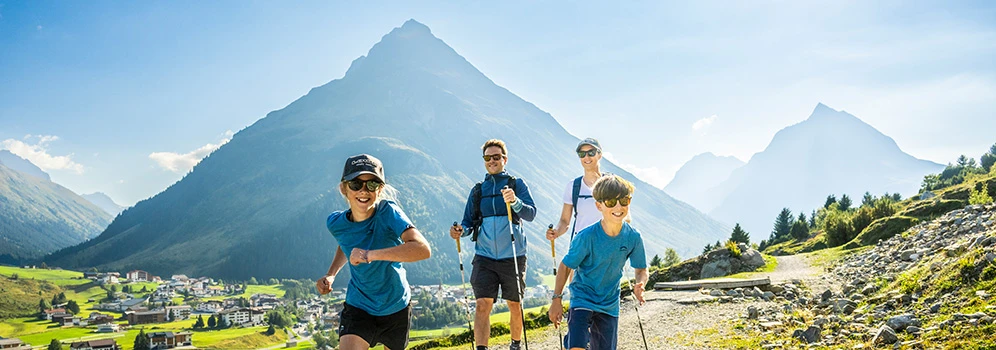 Eine Familie ist unterwegs auf einem Wanderweg mit Bergpanorama