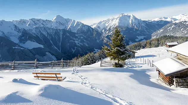 Blick über verschneite Gletscherlandschaft mit Holzhütten 