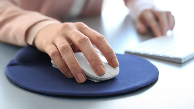 Frau nutzt PC-Maus auf einem Mousepad mit integriertem Gel-Pad