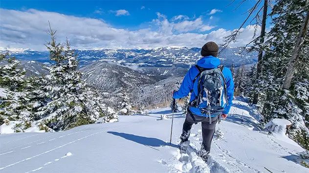 Wanderer blickt auf das verschneite Hochtal Bad Bleiberg
