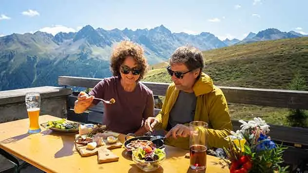 Ein Paar genieß eine Brotzeit auf einer Almhütte