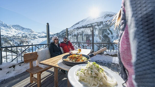 Paar sitzt auf Almhütte und bekommt Kaiserschmarrn serviert