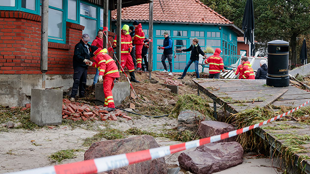Mitarbeiter der Deutschen Lebens-Rettungs-Gesellschaft bilden eine Kette, um herabgestürzte Steine eines Gebäudes einzusammeln. 