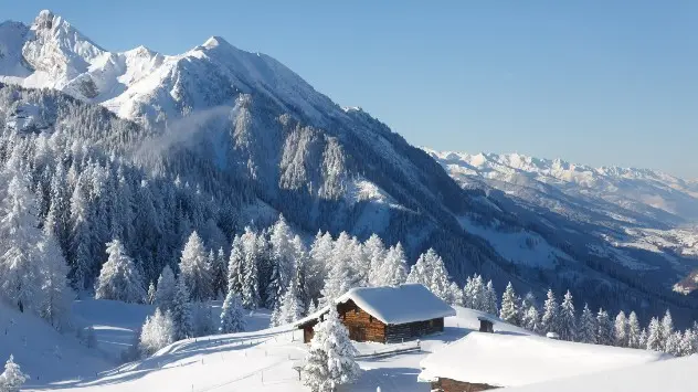 Eine verschneite Winterlandschaft bei strahlendem Sonnenschein in den Alpen.