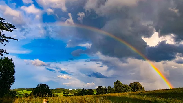 Regenbogen mit Wolken über Feld