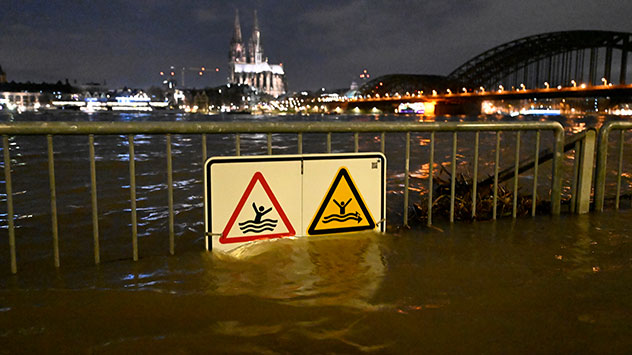 In Köln sind Warnschilder am Rheinufer vom Hochwasser umspült.