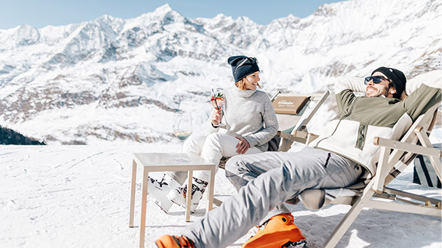 Paar liegt in der Sonne in verschneiter Berglandschaft