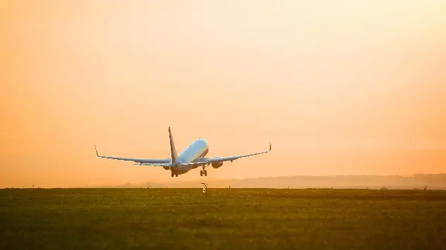 Airplane taking off from runway at sunset