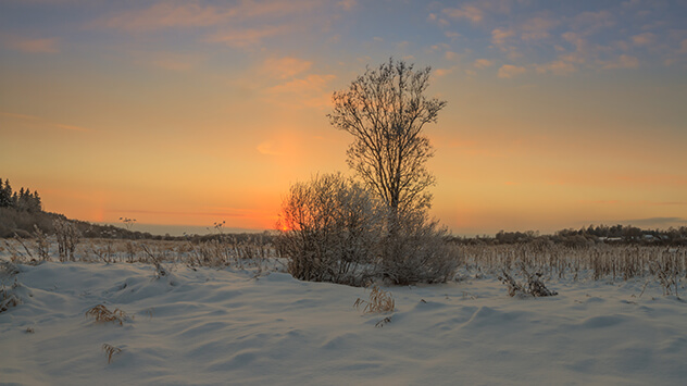 Sonnenuntergang über einer verschneiten weiten Landschaft