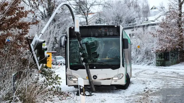 Ein Schulbus ist auf schneeglatter Straße gegen eine Ampel gefahren.