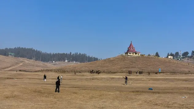 Men play cricket at the ski-resort usually covered in snow at this time of the year 