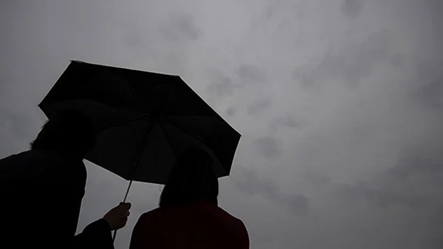 Paar unter schwarzen Regenschirm, schaut in den grau-blauenm Himmel