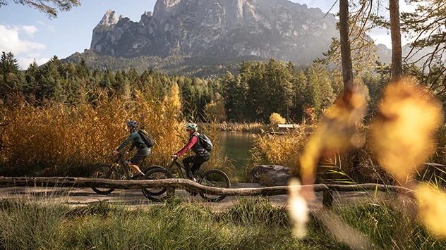 Ein Paar unterwegs mit Mountainbikes, im Hintergrund Dolomitengipfel - Bild: Seiser Alm Marketing / Roschan Fill Ein Paar unterwegs mit Mountainbikes, im Hintergrund Dolomitengipfel