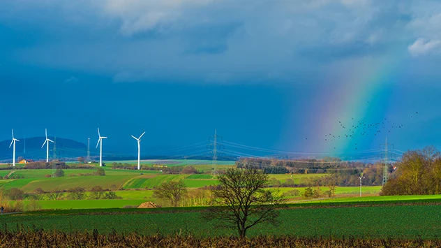 Regenbogen spannt sich mitten im Januar über grüne Felder auf.