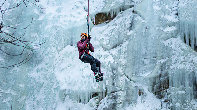 Eine Frau wird am vereisten Klettersteig Gorge Alpin abgeseilt