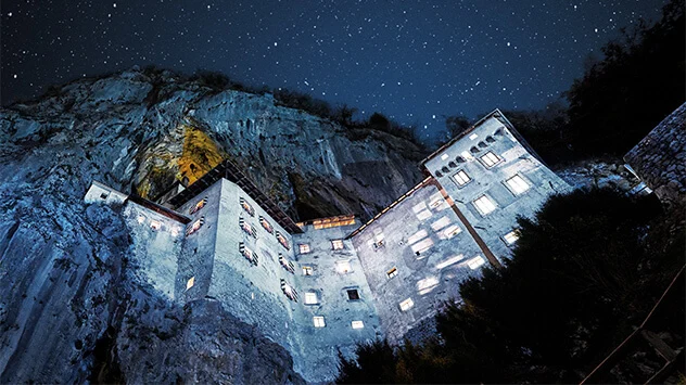 Beleuchtete Felsenburg mit Sternenhimmel bei Nacht