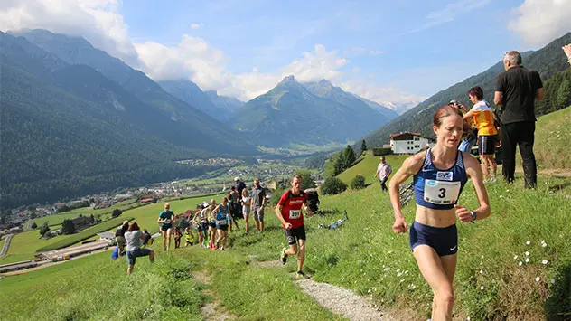 Laufteilnehmer auf einer Trailrunning-Strecke in einem grünen Tal