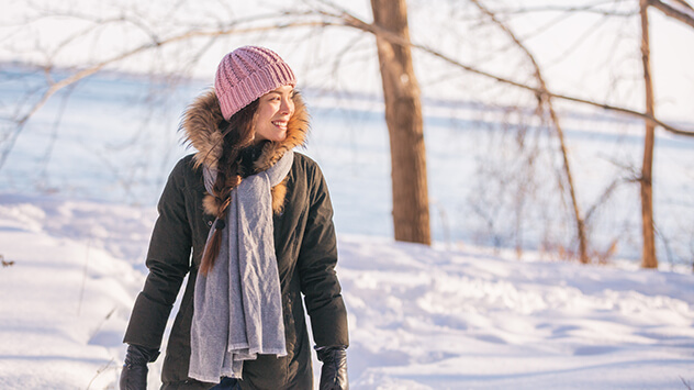 Junge Frau geht in der Sonne im Schnee spazieren