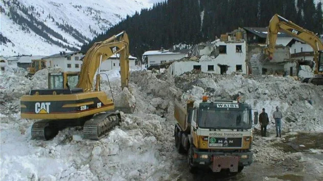 Bagger verladen die extrem verdichteten Schneemassen und Trümmer auf LKWs. 