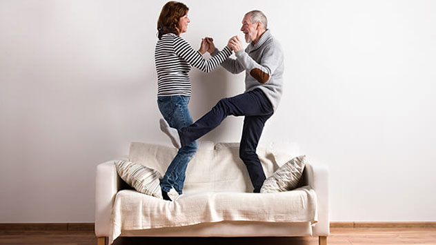Senioren stehen auf Couch und berühren ihre Hände