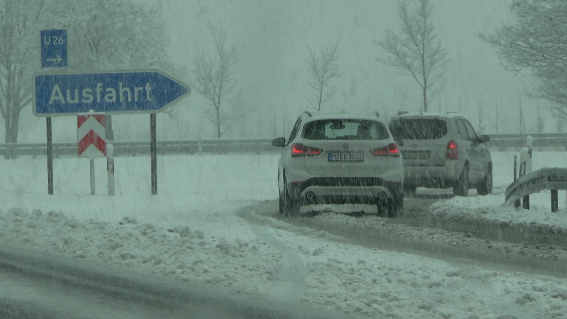 Autos fahren im Schneetreiben von der Autobahn ab