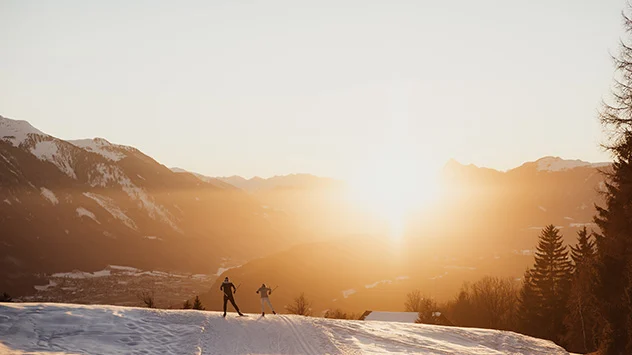 Langläufer auf einer Loipe bei Sonnenaufgang