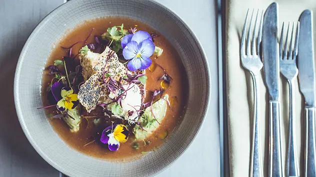 Gazpacho mit essbaren Blüten und frischen Kräutern im Deanes Restaurant in Belfast.