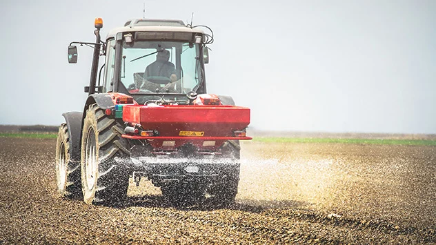 Ein Traktor düngt ein Acker im Frühjahr.
