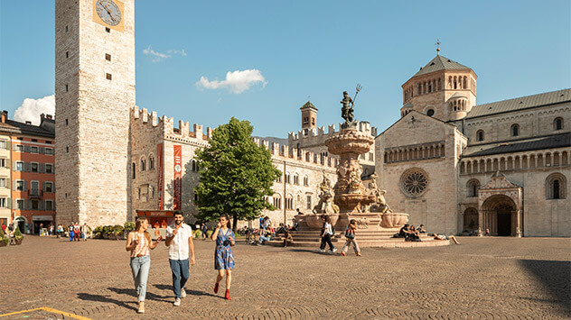 Freunde schlendern Eis essend über die Piazza Duomo in Trento