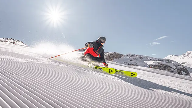 Ein Skifahrer auf einer Piste bei Sonnenschein