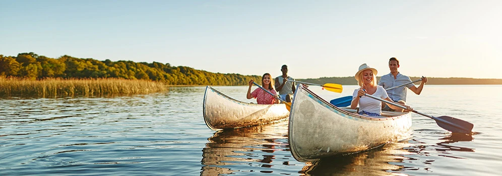 Menschen fahren Kanu in der Abendstimmung auf einem See.