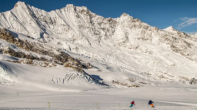 Skifahrer auf einer Piste mit schneebedeckten Bergen im Hintergrund