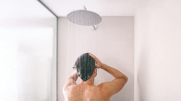 Mann duscht unter Regenwald-Dusche