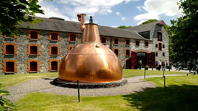 Historische Midleton Distillery in County Cork mit großer kupferner Brennblase im Vordergrund.
