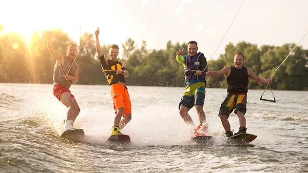 Gruppe junger Männer wakeboarden auf einem See