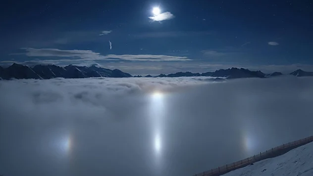 © panomax.com Der Mond spiegelt sich im Eisnebel. Rund herum entfaltet sich ein sogenannter Halobogen mit gleich mehreren Nebenmonden über dem Tal.